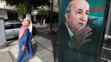 Eine Frau geht an einem Wahlbanner des amtierenden algerischen Präsidenten und des unabhängigen Präsidentschaftskandidaten Abdelmajid Tebboune vorbei, bevor die Präsidentschaftswahlen in Algier, Algerien, am 06. September 2024 stattfinden. Drei Kandidaten, darunter der algerische Präsident Abdelmajid Tebboune, treten bei den Präsidentschaftswahlen am 07. September 2024 an. 