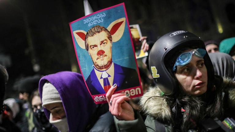 Eine Anhängerin der georgischen Opposition hält eine Karikatur von Micheil Kawelaschwili während eines Protests nach der Wahl von Micheil Kawelaschwili zum neuen georgischen Präsidenten nach der Abstimmung im Parlamentsgebäude während der Präsidentschaftswahlen in Tiflis
