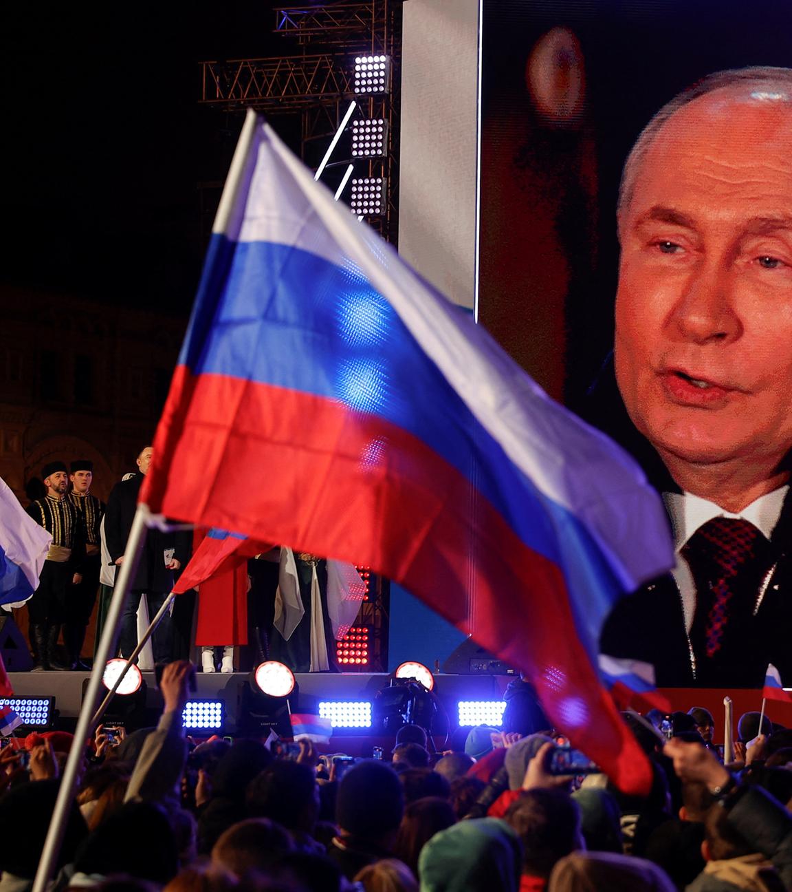 18.03.24, Moskau: Russische Flaggen vor einem Bildschirm, der Putin zeigt.