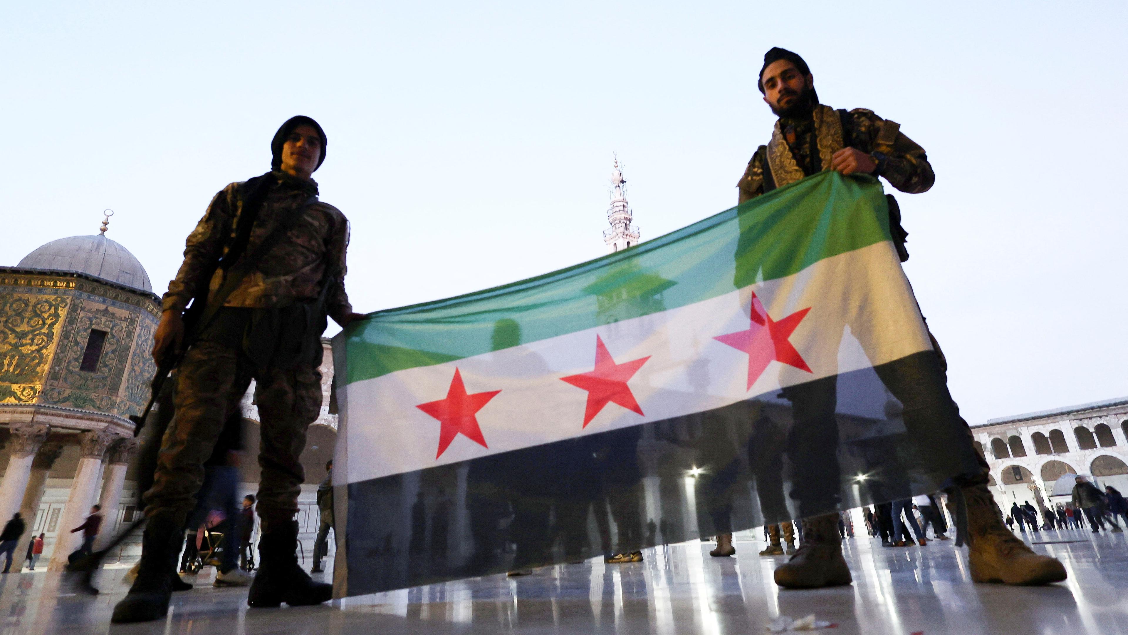 Kämpfer der Rebellen posieren mit einer Fahne der syrischen Opposition in der Umayyaden-Moschee in Damaskus, Syrien, 9. Dezember 2024, nachdem die Rebellen die Hauptstadt erobert und den syrischen Präsidenten Bashar al-Assad gestürzt haben.