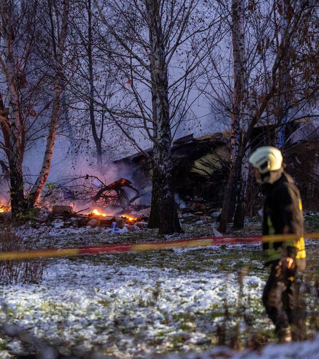 Rettungskräfte gehen an der Absturzstelle in der Nähe des internationalen Flughafens von Vilnius am Wrack der DHL-Frachtmaschine vorbei, 25.11.2024