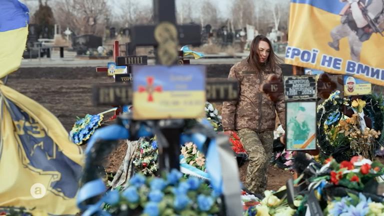 Auf dem Bild ist eine Soldatin auf dem Friedhof zu sehen.