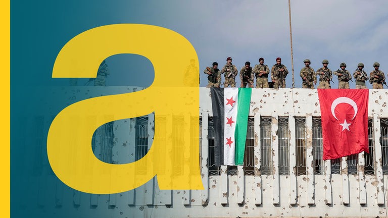 Tuerkische soldaten (r) und syrische ooppositionelle Kämpfer, die mit der Türkei verbuendet sind, stehen auf einem Gebäuude, von dem eine syrische und eine türkische Flagge hängen.