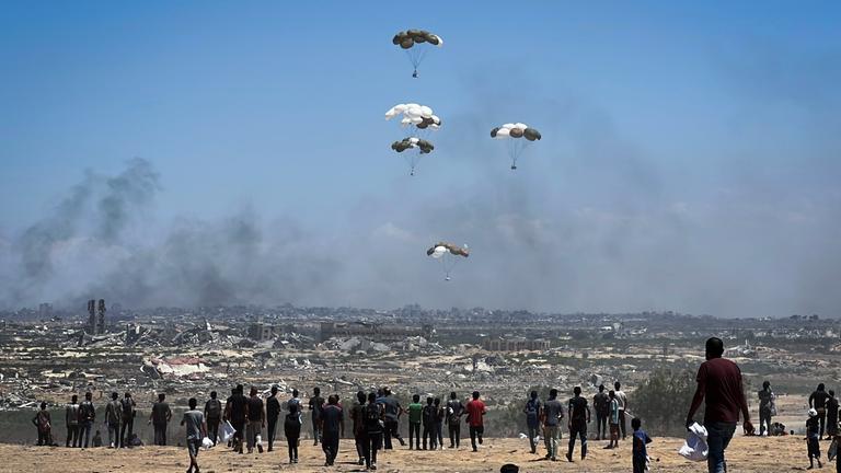 Nusairat, Gazastreifen, Palästinensisches Gebiet: Palästinenser eilen zum Ort des Geschehens, als Luftpaletten mit humanitären Hilfsgütern über Nuseirat im zentralen Gazastreifen aus einem Militärflugzeug abgeworfen werden und mit Fallschirmen herabgleiten. Dies geschieht im Rahmen einer Luftabwurfmission über dem von Israel belagerten palästinensischen Gebiet am 5. August 2025.