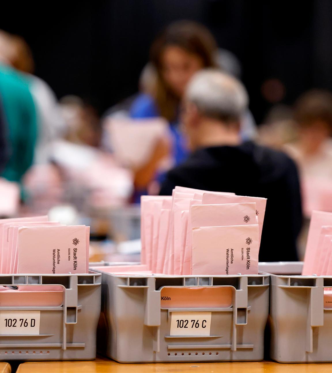 Briefwahlunterlagen zur Kommunalwahl in NRW liegen im Briefwahlzentrum Köln auf Tischen in Kisten. Bei der Auszählung der Briefwahlstimmen im Briefwahlzentrum in der Koelnmesse werden die roten Wahlbriefe von ehrenamtlichen Wahlhelfern auf ihre Gültigkeit überprüft.