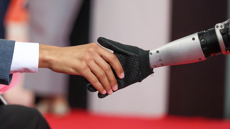 Ein mensch und ein Roboter geben sich die Hand