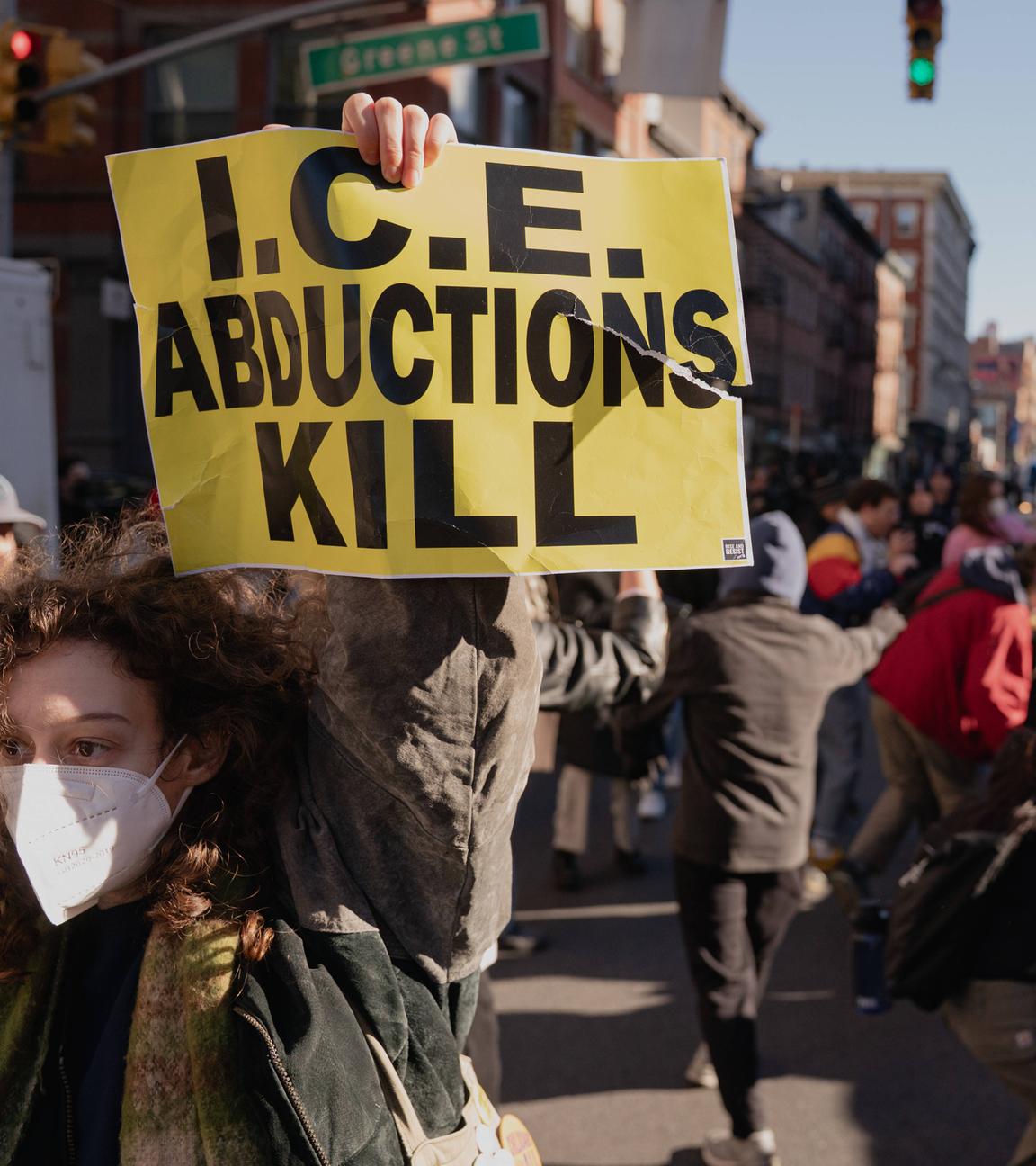 Ein Demonstrant hält ein Plakat mit der Aufschrift „ICE Abductions Kill“ (ICE-Entführungen töten) hoch, während Beamte der Einwanderungs- und Zollbehörde (ICE) vor einer geplanten Razzia in der Canal Street in Manhattan von Demonstranten konfrontiert werden. Die ICE ist in New York City hart gegen Verkäufer von gefälschten Waren vorgegangen.