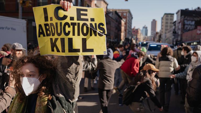 Ein Demonstrant hält ein Plakat mit der Aufschrift „ICE Abductions Kill“ (ICE-Entführungen töten) hoch, während Beamte der Einwanderungs- und Zollbehörde (ICE) vor einer geplanten Razzia in der Canal Street in Manhattan von Demonstranten konfrontiert werden. Die ICE ist in New York City hart gegen Verkäufer von gefälschten Waren vorgegangen.