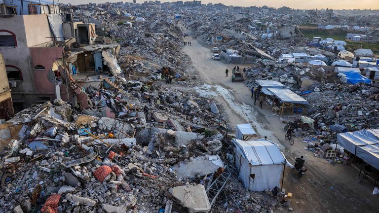 Palestinians walk amid the rubble of buildings in Beit Lahia in the northern Gaza Strip on March 4, 2025,