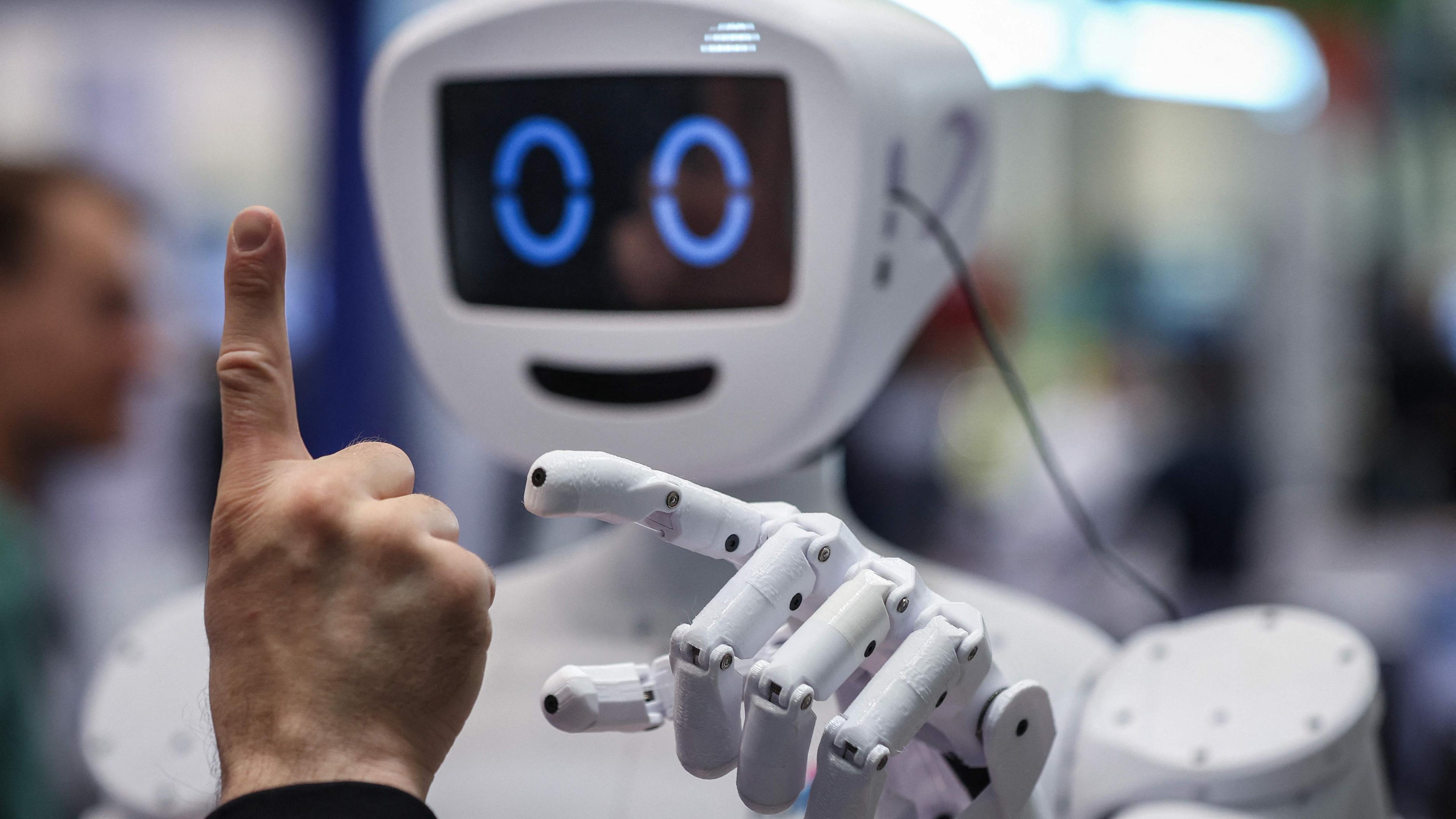 Ein Mann interagiert mit PIB (Printable Intelligent Bot), einem 3D-druckbaren humanoiden Roboter, am Stand des deutschen Bundesministeriums für Bildung und Forschung