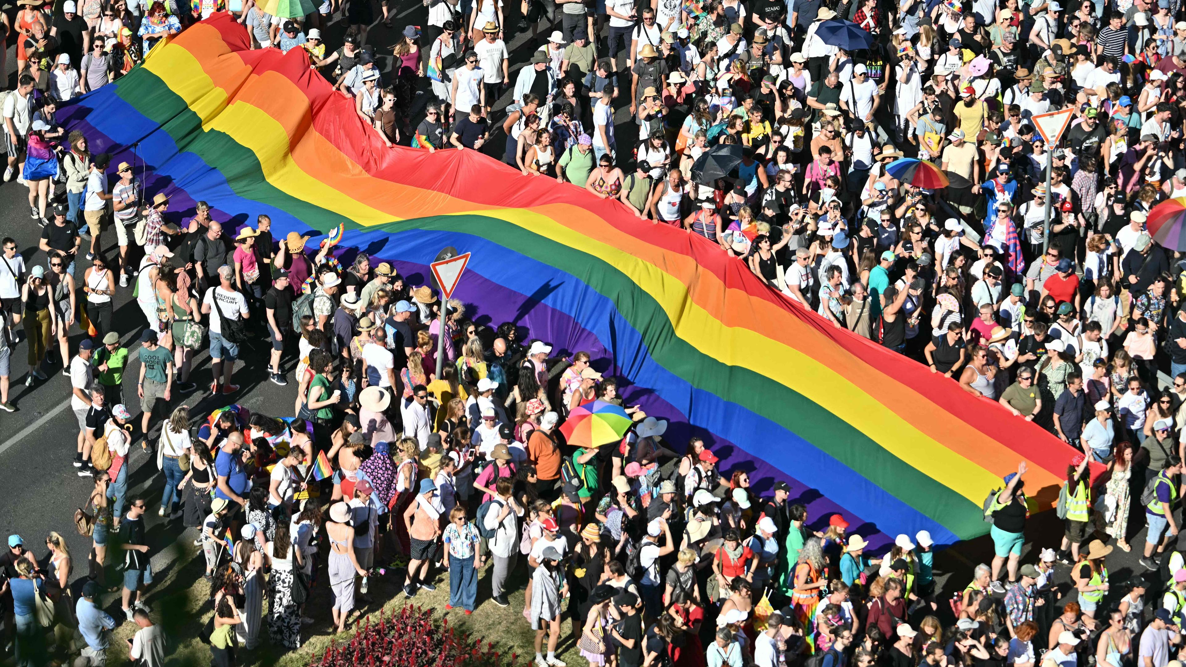 Menschen tragen eine Regenbogenflagge, während sie an der Budapester Pride-Parade in der Innenstadt von Budapest am 28. Juni 2025 teilnehmen.