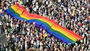 Menschen tragen eine Regenbogenflagge, während sie an der Budapester Pride-Parade in der Innenstadt von Budapest am 28. Juni 2025 teilnehmen.