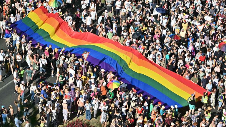 Menschen tragen eine Regenbogenflagge, während sie an der Budapester Pride-Parade in der Innenstadt von Budapest am 28. Juni 2025 teilnehmen.