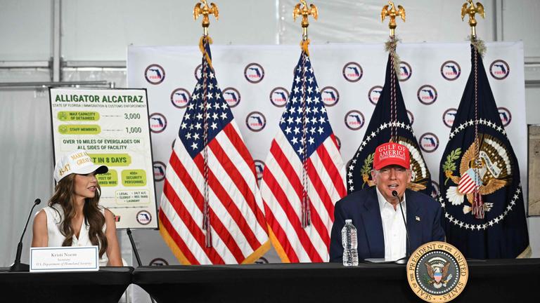 US President President Donald Trump speaks as US Secretary of Homeland Security Kristi Noem (L) looks on after touring a migrant detention center, dubbed "Alligator Alcatraz," located at the site of the Dade-Collier Training and Transition Airport in Ochopee, Florida on July 1, 2025.