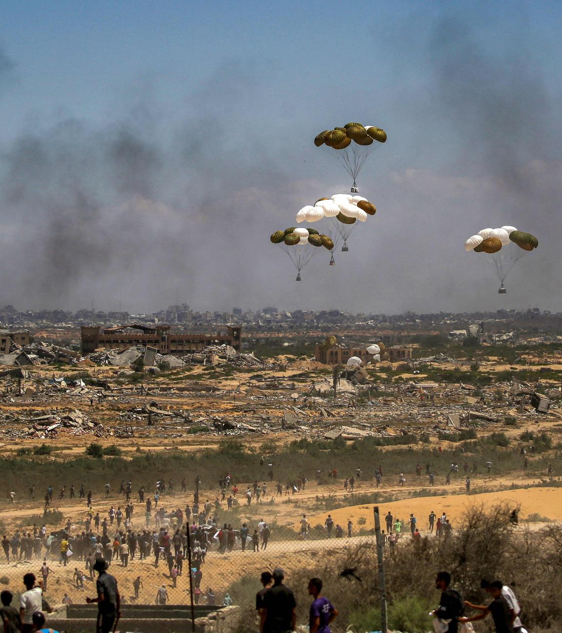 Palästinenser eilen zum Ort des Geschehens, als Hilfsgüterpaletten aus einem Militärflugzeug über Nuseirat im zentralen Gazastreifen abgeworfen werden, während einer Luftabwurfmission über dem von Israel belagerten palästinensischen Gebiet am 5. August 2025. 