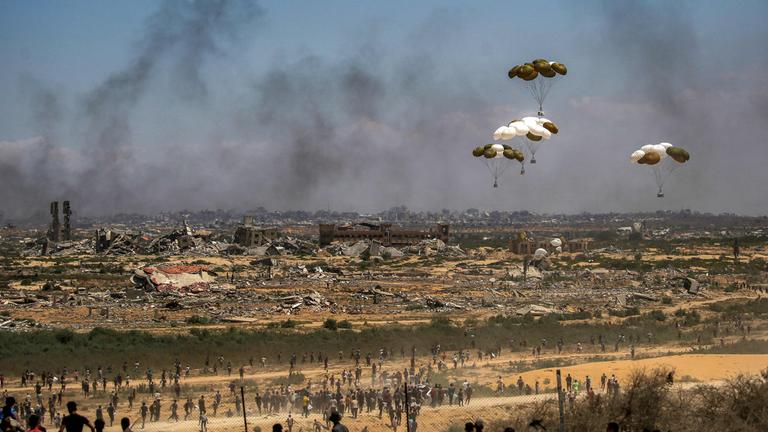 Palästinenser eilen zum Ort des Geschehens, als Hilfsgüterpaletten aus einem Militärflugzeug über Nuseirat im zentralen Gazastreifen abgeworfen werden, während einer Luftabwurfmission über dem von Israel belagerten palästinensischen Gebiet am 5. August 2025. 