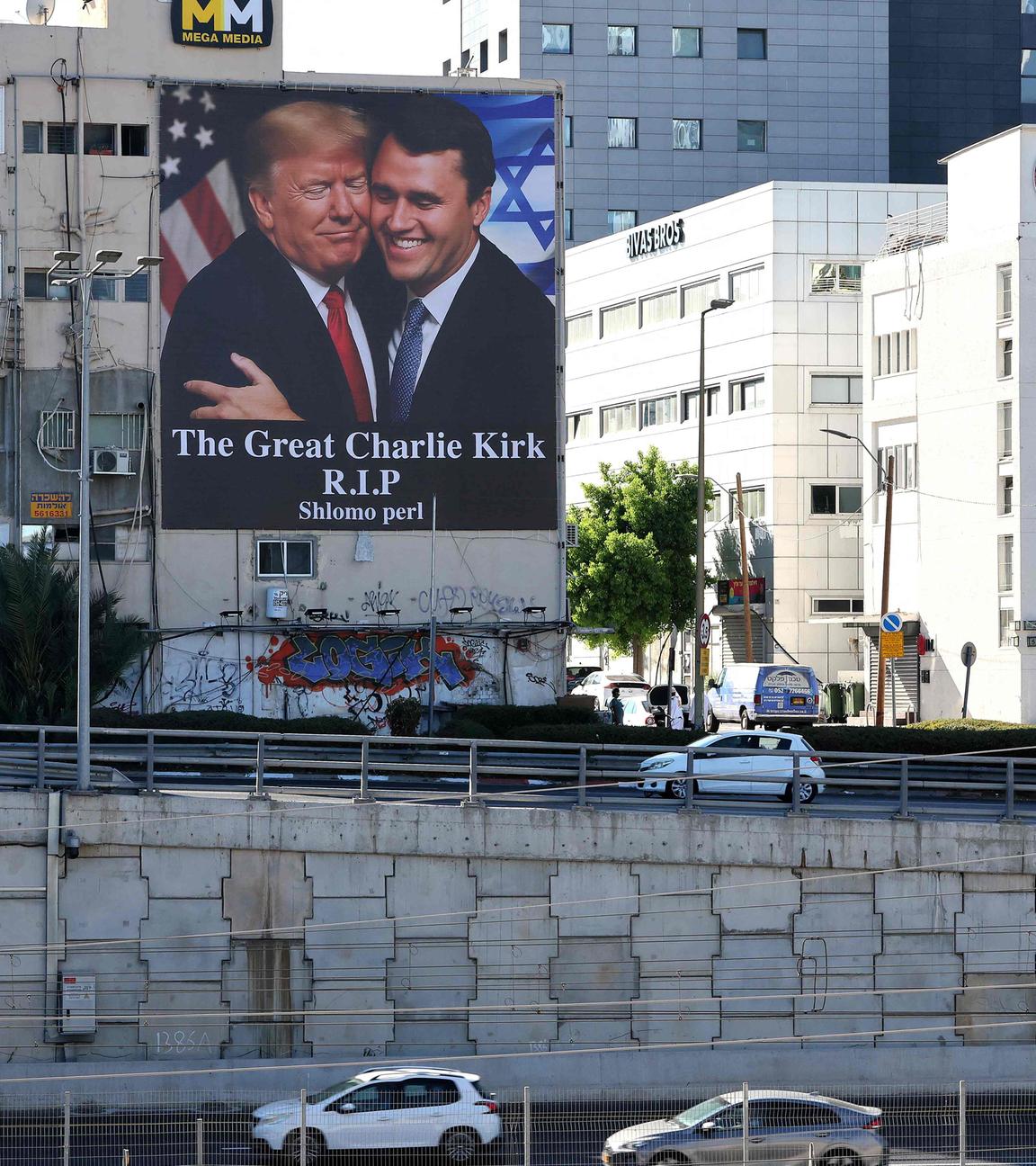 Eine Plakatwand mit einem Bild von US-Präsident Donald Trump (links), der Charlie Kirk umarmt, hängt am 13.September 2025 an der Seite eines Gebäudes in Tel Aviv