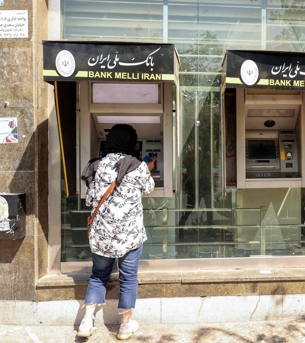 Menschen heben am 28. September 2025 in der iranischen Hauptstadt Teheran Geld an einem Geldautomaten ab.