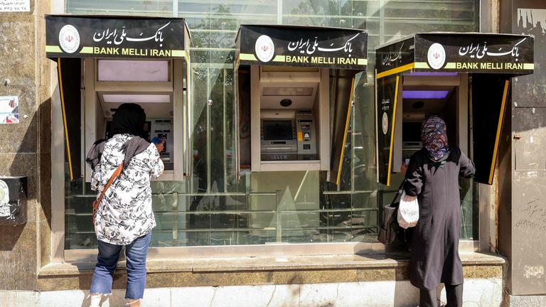 Menschen heben am 28. September 2025 in der iranischen Hauptstadt Teheran Geld an einem Geldautomaten ab.