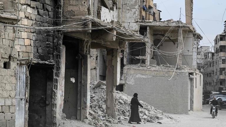 Eine Frau geht am 4. November 2025 an Stromkabeln vorbei, die entlang beschädigter Gebäude im Stadtteil Ain Tarma am östlichen Rand der Hauptstadt Damaskus verlaufen. Im vergangenen Monat erhöhte das syrische Energieministerium die Preise um mindestens das 60-Fache gegenüber dem bisherigen Tarif, was bei der Bevölkerung, die bereits unter jahrzehntelangen Sanktionen und 14 Jahren Krieg leidet, für Entsetzen sorgte.