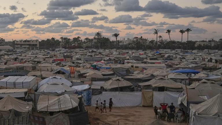 Die Dämmerung bricht herein, während eine Gruppe Palästinenser vor einem Zelt in einem provisorischen Lager in Deir al-Balah im zentralen Gazastreifen sitzt, Montag, 6. Oktober 2025.