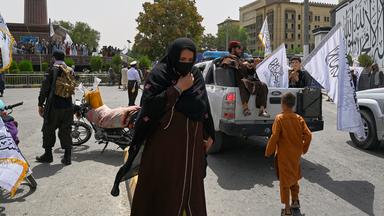 Frau läuft durch Menge von Taliban Kämpfern