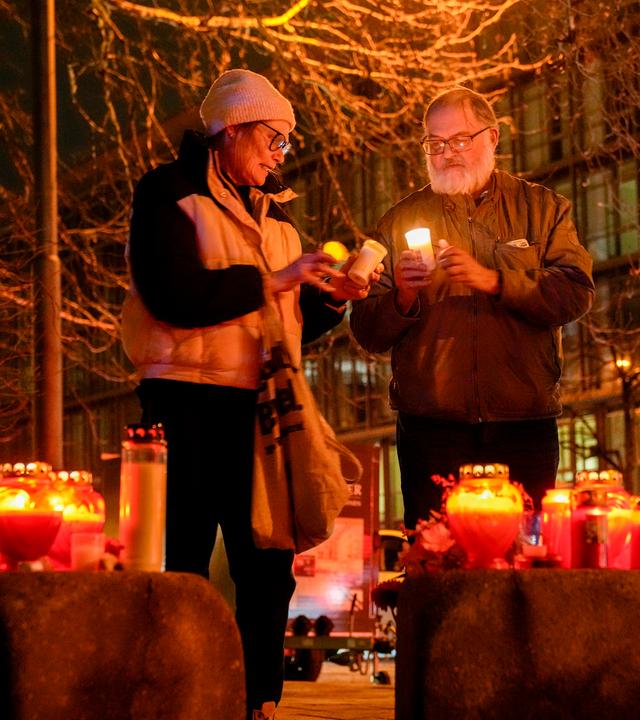 People light candles at the scene where a driver drove a car into a labor union demonstration in Munich, Germany, Thursday Feb. 13, 2025.