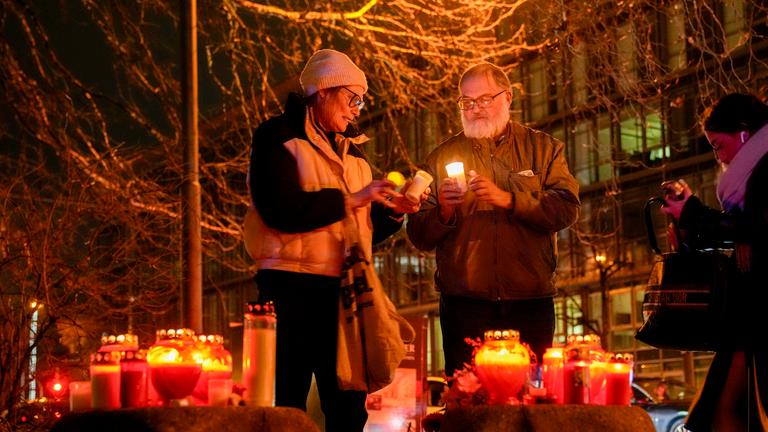 People light candles at the scene where a driver drove a car into a labor union demonstration in Munich, Germany, Thursday Feb. 13, 2025.