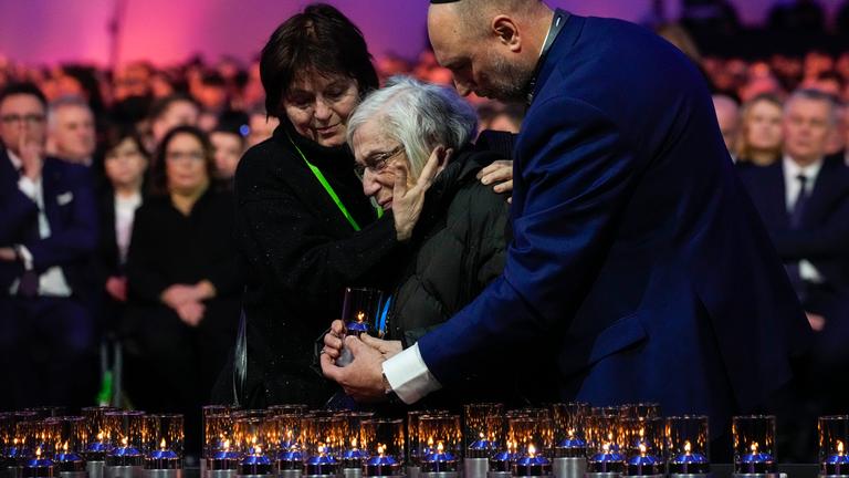 A holocaust survivor gets a hug after placing a lilt candle at the Auschwitz-Birkenau former Nazi German concentration and extermination camp, during a ceremony marking the 80th anniversary of its liberation, in Oswiecim, Poland, Monday, Jan. 27. 2025. (AP Photo/Czarek Sokolowski)