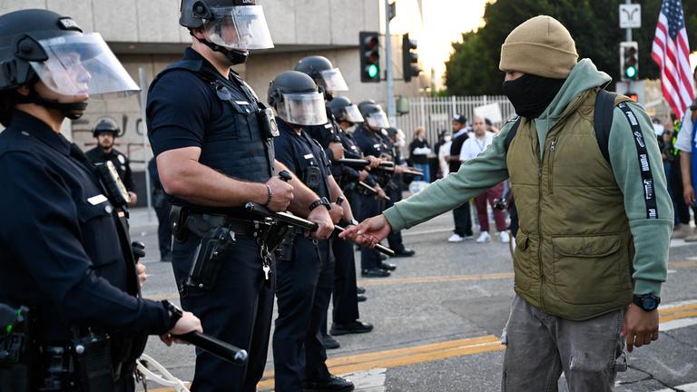 Demonstrant Polizisten LA mit USA Flagge im Hintergrund