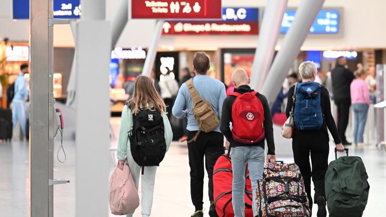 Nordrhein-Westfalen, Düsseldorf: Reisende mit Gepäck gehen in der Abflughalle des Flughafens zur Halbzeit der Sommerferien. Viele Reisende starten jetzt in den Urlaub oder kehren zurück. 