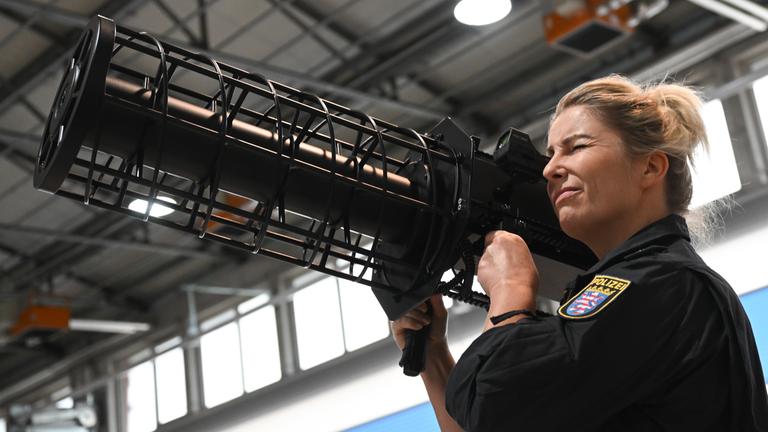 08.10.2025, Hessen, Egelsbach: Eine Oberkommissarin der Polizeifliegerstaffel Hessen demonstriert im Kompetenzzentrum Drohnen den Einsatz eines Jammers. Jammer sind Geräte, die Hochfrequenzsignale aussenden, um die Kontrolle der Drohne zu stören oder vollständig zu blockieren. Das Kompetenzzentrum existiert seit 2019, seit Ende 2024 gibt es gesetzliche Regelungen im hessischen Polizeigesetz für Einsatz, Detektion und Abwehr von Drohnen.