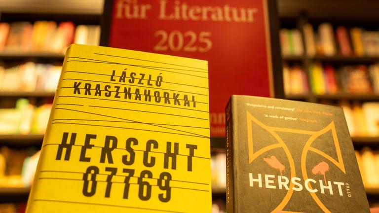  Bücher des ungarischen Schriftstellers László Krasznahorkai stehen im Berliner Kulturkaufhaus Dussmann vor einem vor einem Aufsteller mit der Aufschrift «Nobelpreis für Literatur 2025»