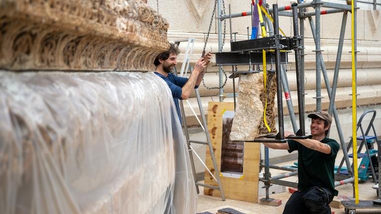  Arbeiter heben im Pergamonmuseum ein Element der Mschatta-Fassade auf eine Palette, aufgenommen während eines Rundgangs durch die künftigen Räume der Antikensammlung und des Museums für Islamische Kunst. Nach Abschluss der Bauarbeiten sollen Mittelbau und Nordflügel des Museums im Jahr 2027 wieder öffnen.