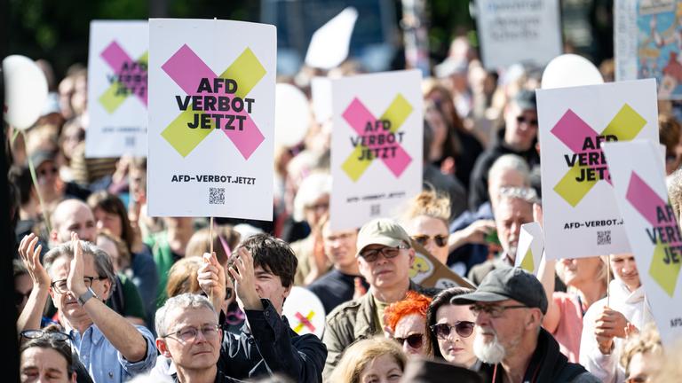 Berlin: Personen halten am bundesweiten Aktionstag "Keine Ausreden mehr - AfD-Verbot jetzt!" am Brandenburger Tor Schilder mit der Aufschrift _AfD Verbot jetzt_ in die Höhe.