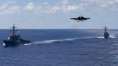 Auf diesem von der Pressestelle des Pentagons zur Verfügung gestellten Bild fahren die Lenkwaffenzerstörer der Arleigh-Burke-Klasse USS Mahan (l, DDG 72) und USS Bainbridge (DDG 96) in Formation, während ein F/A-18 Super Hornet des Carrier Air Wing Eight zur Landung auf dem Flugzeugträger USS Gerald R. Ford (CVN 78) ansetzt.