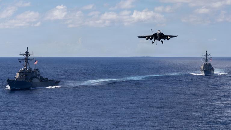Auf diesem von der Pressestelle des Pentagons zur Verfügung gestellten Bild fahren die Lenkwaffenzerstörer der Arleigh-Burke-Klasse USS Mahan (l, DDG 72) und USS Bainbridge (DDG 96) in Formation, während ein F/A-18 Super Hornet des Carrier Air Wing Eight zur Landung auf dem Flugzeugträger USS Gerald R. Ford (CVN 78) ansetzt.