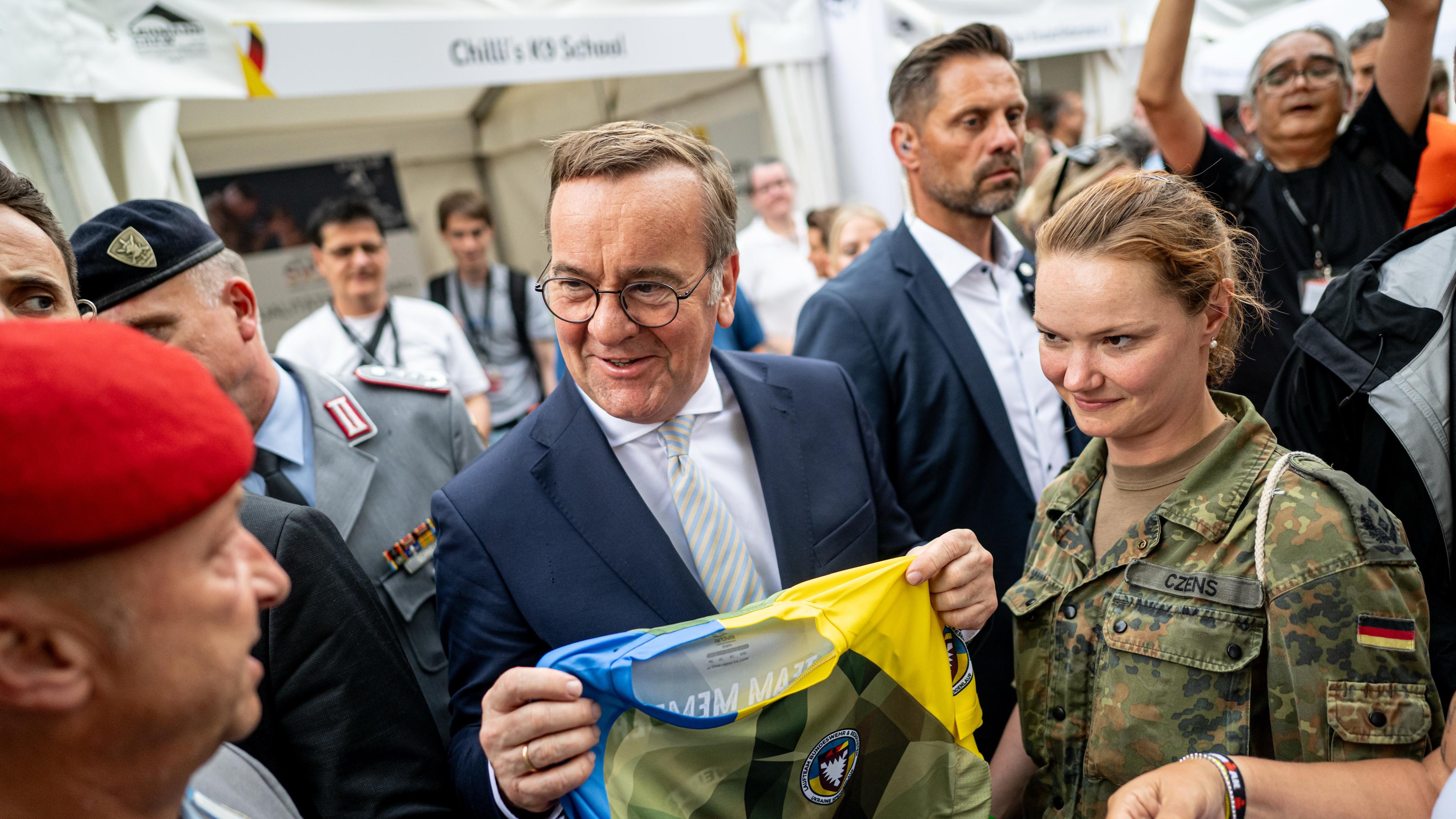 Boris Pistorius (SPD), Bundesminister der Verteidigung, bekommt am Nationalen Veteranentag auf dem Bürgerfest rund um das Reichstagsgebäude ein Trikot vom Laufteam Bundeswehr