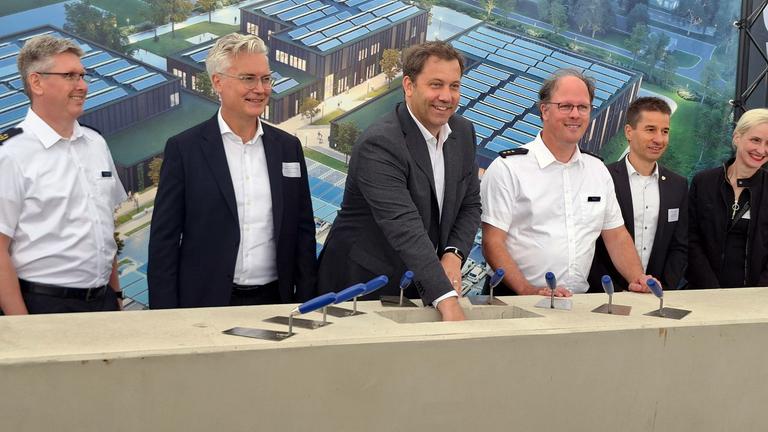 Lars Klingbeil (SPD, 3.v.l.), Bundesminister der Finanzen und Vizekanzler, steht bei der Grundsteinlegung für ein Einsatztrainingszentrum des Zolls