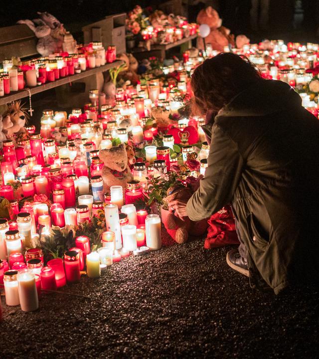 23.01.2025, Bayern, Aschaffenburg: Eine Person legt nach der tödlichen Messerattacke im Park Schöntal einen Teddybären bei einer Gedenkstätte nieder. 