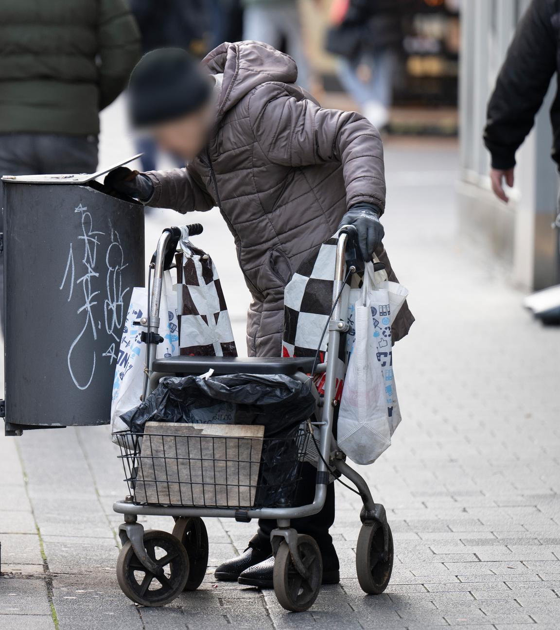 Hessen, Offenbach: Eine alte Frau sucht in Mülleimern in der Innenstadt von Offenbach nach Pfandflaschen