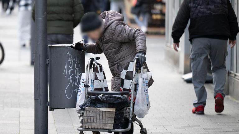 Hessen, Offenbach: Eine alte Frau sucht in Mülleimern in der Innenstadt von Offenbach nach Pfandflaschen