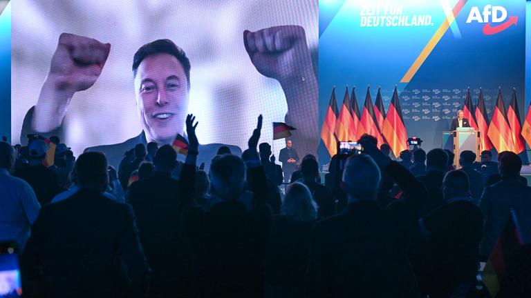 Über eine Videoeinblendung unterhält sich US-Miliardär Elon Musk mit Alice Weidel (r), Bundesvorsitzende der AfD, beim Wahlkampfauftakt der AfD.