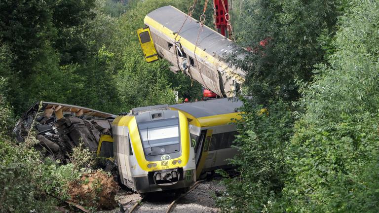28.07.2025, Baden-Württemberg, Riedlingen: Mit einem Kran wird an der Unfallstelle, an der ein Regionalzug entgleist ist, ein Waggon angehoben.