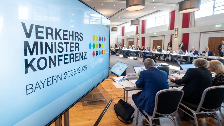 Bayern, Straubing: ÂVerkehrsministerkonferenz Bayern 2025/2026Â steht auf dem Monitor bei der Tagung von Bund und Ländern. Diskutiert werden unter anderem Infrastrukturfonds, Deutschlandticket, Schienenverkehr, E-Mobilität, Fahrschulreform und Luftverkehr