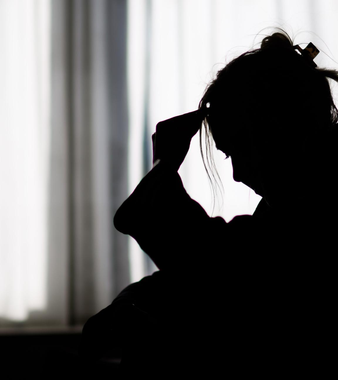 Silhouette einer Frau vor einer hellen Fensterfront
