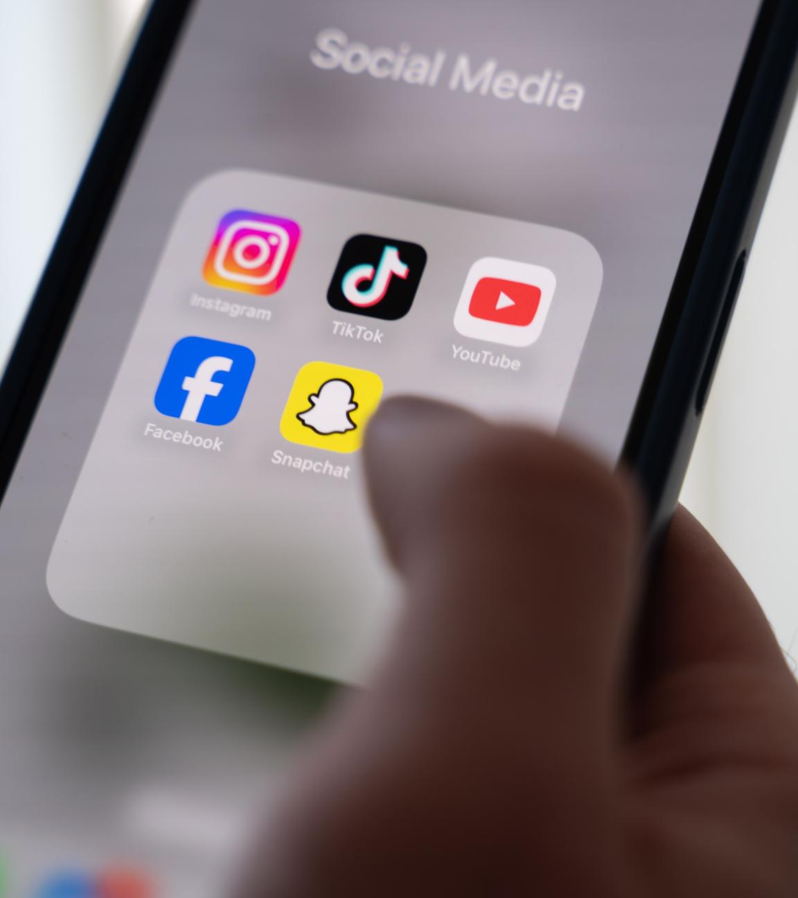 Eine Frau hält ein Smartphone, auf dessen Display verschiedene Social Media Apps angezeigt werden. Videos von Parteien an den politischen Rändern werden einer Studie zufolge deutlich häufiger auf sozialen Medien wie Instagram und Tiktok angezeigt als die der Mitte-Parteien.