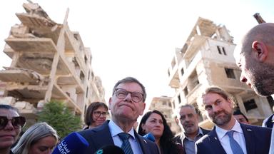 Syrien, Harasta: Johann Wadephul (M, CDU), Bundesminister des Auswärtigen, steht während seines Besuchs eines humanitären Projekts mit Raed Saleh (r), Minister für Katastrophenschutz in Syrien, in einer Straße vor während des Bürgerkriegs zerstörten Häusern. Bei seinem Besuch in Syrien zeigt sich Außenminister Wadephul erschüttert über das Ausmaß an Zerstörung.