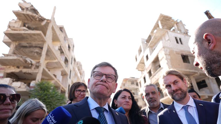 Syrien, Harasta: Johann Wadephul (M, CDU), Bundesminister des Auswärtigen, steht während seines Besuchs eines humanitären Projekts mit Raed Saleh (r), Minister für Katastrophenschutz in Syrien, in einer Straße vor während des Bürgerkriegs zerstörten Häusern. Bei seinem Besuch in Syrien zeigt sich Außenminister Wadephul erschüttert über das Ausmaß an Zerstörung.