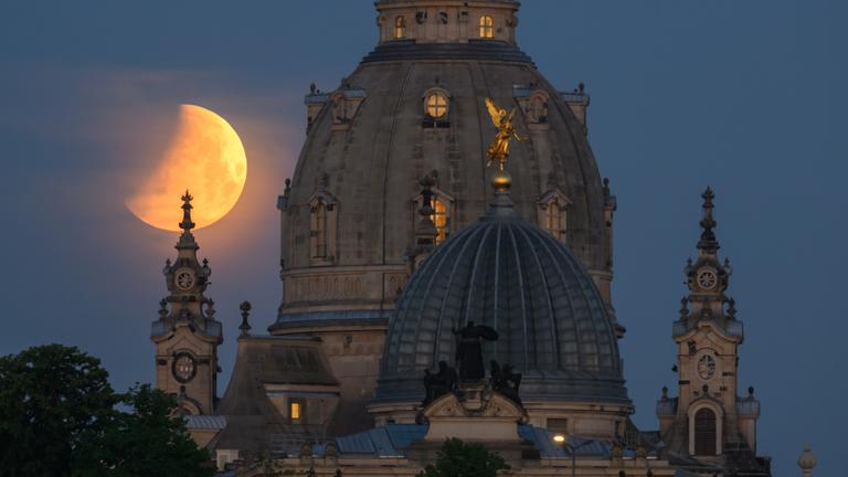 achsen, Dresden: Der Mond geht am Morgen während einer partiellen Mondfinsternis hinter der Frauenkirche und der Kuppel der Kunstakedmie mit dem Engel Fama unter. Am Sonntag wird sich der Mond nach und nach in den Erdschatten schieben - bis hin zur totalen Mondfinsternis.